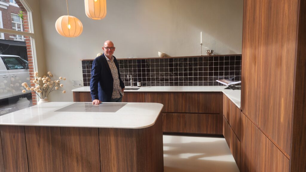 Luxe maatwerkkeuken met walnootkleurige fronten, wit werkblad, kookeiland en moderne verlichting, professioneel geplaatst door DNNK Keukenmontage.